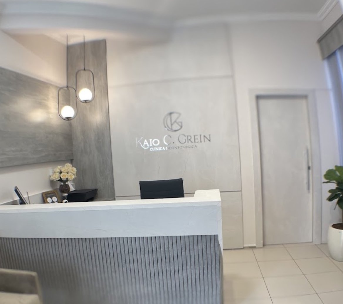 Recepção da Clínica Odontológica Dr. Kaio Cesar Grein, em tons claros com o logotipo na parede